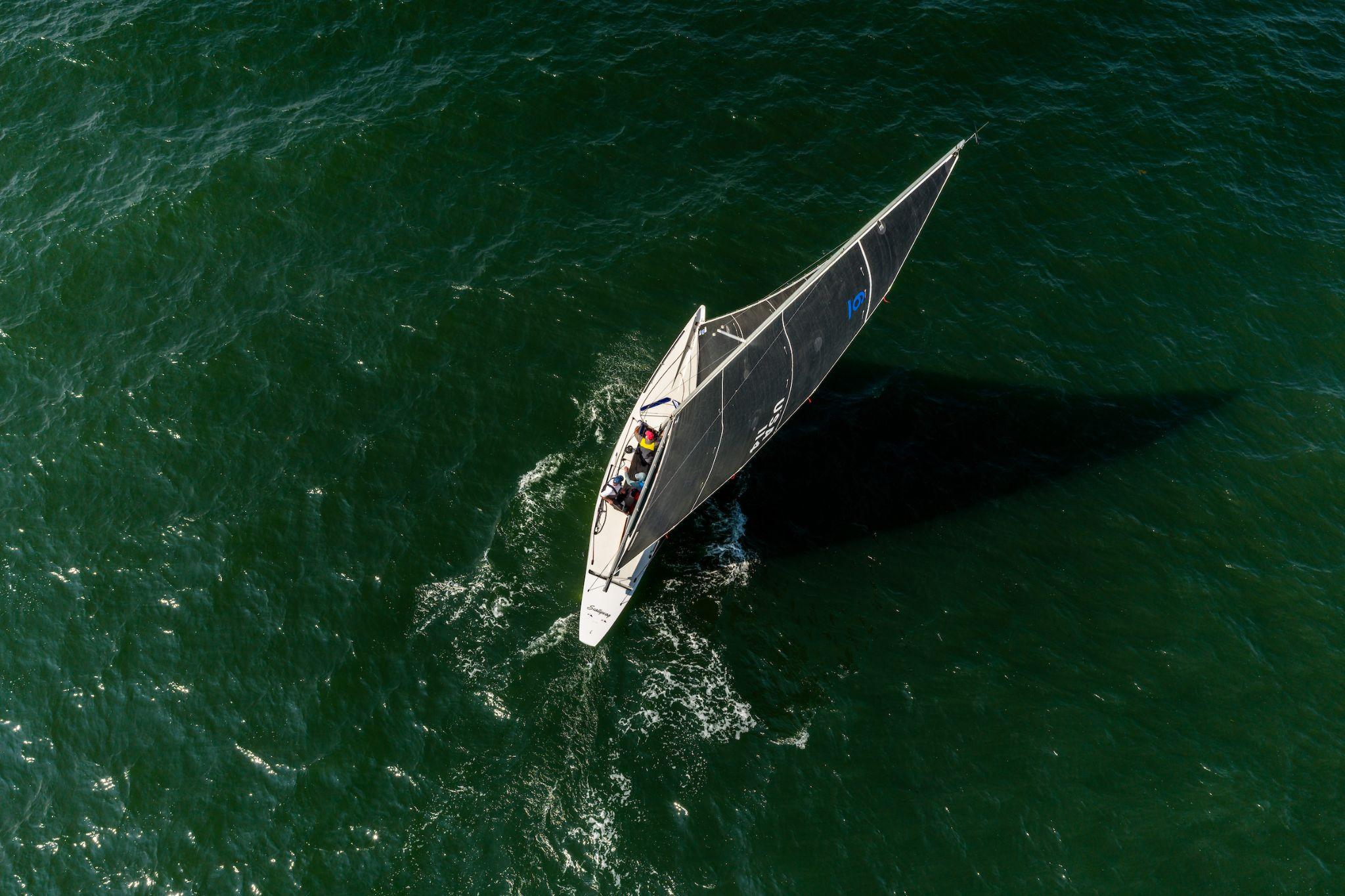 Aerial view of a 6mR yacht sailing on dark green water
